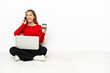 © luismolinero - Young caucasian woman with a laptop sitting on the floor holding coffee to take away and a mobile