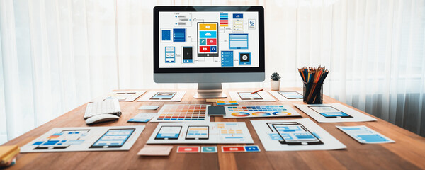 Digital and paper wireframe designs for web or mobile app UI UX display on laptop computer screen. Panoramic shot of developer workspace for brainstorming and design application framework. Scrutinize