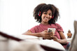 African American woman using the smartphone and listening musics on the sofa