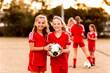 © Austockphoto - Two tween football players standing together at a sports oval holding a soccer ball