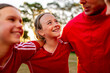 © Austockphoto - Close-up of female tween football team players in a huddle preparing for a game