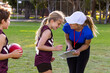 © Austockphoto - female sports coach interacting with young girl football player with clipboard