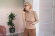 © BullRun - Mature woman having phone call in living room