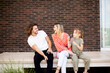 © BGStock72 - Family with a mother, father and daughter sitting outside on the steps of a front porch of a brick house