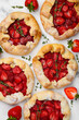 Strawberry mini galette or open pie decorated with thyme and powdered sugar on a marble background. Summer berry dessert. Top view. Close up