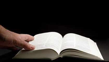 open Bible and man  hand lying on the page юselective focus . High quality photo