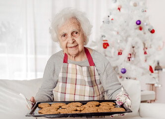 Senior woman holding oven cooker with baked cookies