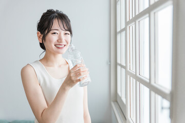 Poster - 家でペットボトルの水・ミネラルウォーター・白湯を飲むリラックスした女性
