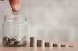 © THAWEERAT - Saving finance business investment concept. Hand of male or female putting coins in jar with money stack step growing growth saving money. Investment And Interest Concept.