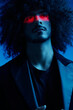 © SHOTPRIME STUDIO - Fashion portrait of a man with curly hair on a blue background with a red stripe of light, multicolored light, trendy, modern concept.
