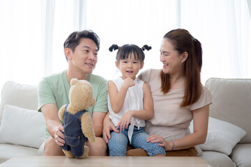 Happiness asian family father and mother and daughter sitting on sofa in living room at home, happy dad and mom and kid sitting and relax with comfortable on couch together, lifestyles concept.