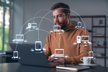 Thoughtful businessman in casual wear typing on laptop at office workplace. Concept of distant work, business, internet surfing, information technology. Social network hologram