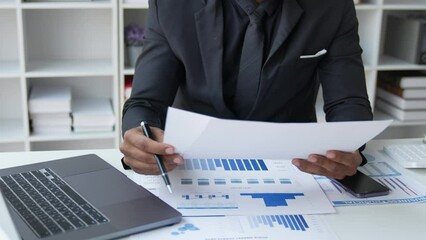 Wall Mural - Asian businessman working in the office, calculating financial reports, organizing paperwork using a laptop and calculator as an aid. management concept accounting.	