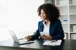 © Nuttapong punna - African Woman freelancer is working her job on computer tablet and laptop Doing accounting analysis report real estate investment data, Financial at office