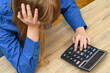Załamana kobieta licząca na kalkulatorze, siedząca przy biurku
