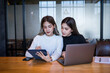 © EduLife Photos - Two cheerful young Asian female college students working on the school project using laptop computers and tablets together in private study room