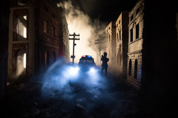 Wall Mural - Police raid at night and you are under arrest concept. Silhouette of handcuffs with police car on backside. Image with the flashing red and blue police lights at foggy background. Slider shot