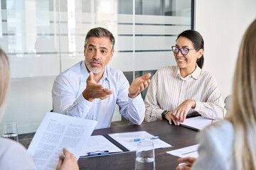 Professional international executive people working at team office meeting. Diverse busy corporate leaders managers discussing project management plan together in teamwork sitting at boardroom table.