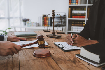 Wall Mural - An attorney or legal advisor is carefully reading the validity of investment documents and signing agreements. with a raised hammer in agreement summarizing the concept of justice administration.