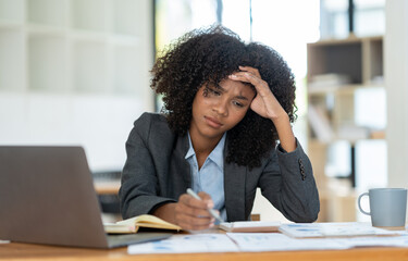 Tired American businesswoman having a headache at work Feeling sick at work while communicating via laptop and discussing various work issues at the office.