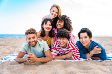 Group of young best friends bonding outdoors - Multiracial happy people having party at the beach during summertime