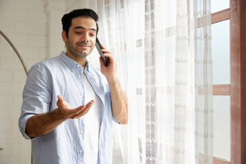 young handsome man talking by smartphone at home