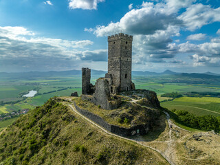 Aerial view of the remains of Hazmburk medieval castle with a circular and rectangular tower sit at the summit of this low peak hiking spot with scenic views. 