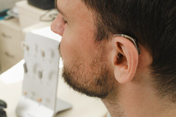 Man trying modern compact hearing aids. Closeup of patient ear. Hearing rehabilitation clinic selecting digital device for middle age deaf people.