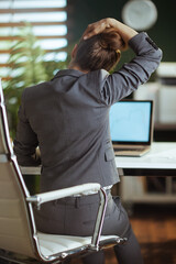 Wall Mural - business owner woman in green office stretching neck