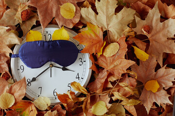 Wall Mural - autumn background with clock, sleeping mask and leaves