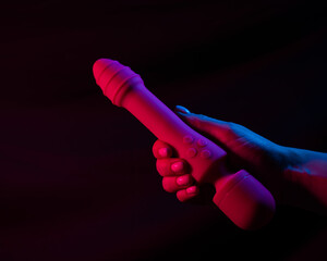 Wall Mural - Woman holding a vibrator in neon pink and blue light.