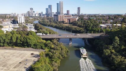 Wall Mural - Aerial drone view above Parramatta River in Greater Western Sydney, NSW, Australia with Parramatta CBD in the background as a ferry travels to Parramatta Wharf  