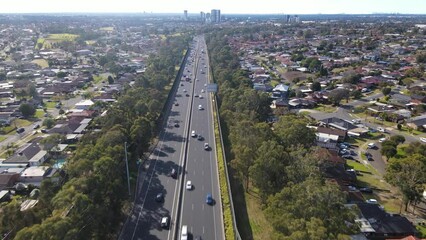 Wall Mural - Aerial drone view above the South Western M5 Motorway at Casula in Sydney, NSW Australia with Liverpool CBD in the background 