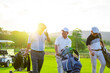 Group of Asian businessman and senior CEO holding golf bag walking on golf course with talking together. Healthy people enjoy outdoor sport lifestyle golfing at country club on summer holiday vacation