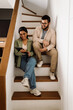© Drobot Dean - Two cheerful coworkers talking while sitting on stairs in office