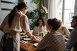 © Drobot Dean - Young waitress serving group of cheerful friends in restaurant