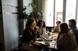 © Drobot Dean - Group of cheerful friends talking while dining in restaurant