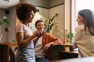 Wall Mural - Beautiful waitress serving young couple in cafe