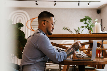 Business owner works with financial bills and calculates profit while sitting in cafe