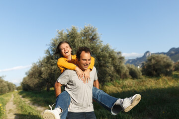 Couple in love. Boyfriend carrying his girlfriend on piggyback. Love and tenderness, dating, romance. Lifestyle concept. Middle age people