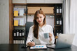 © laddawan - Young beautiful woman typing on tablet and laptop while sitting at the working wooden table office.