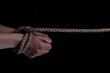 Tied hands with a rope on a black background