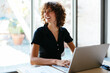 © Westend61 - Happy young businesswoman sitting with laptop at desk