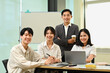 © Prathankarnpap - Group of company employees sitting in modern office and smiling confidently to camera