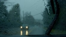 Passenger view from car driving in heavy rain, windshield wipers on.