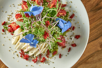 Wall Mural - Vegetarian salad with cherry tomatoes, salad mix, tofu cheese and pesto sauce in a plate