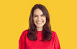 © Studio Romantic - Full-face shot of beautiful young brunette girl in red sweater looking into the camera with happy, funny expression on her face. Studio portrait of happy young woman on isolated yellow background.