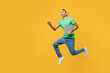 © ViDi Studio - Full body young IT man of African American ethnicity wearing casual clothes green t-shirt hat jump high hold closed laptop pc computer run fast isolated on plain yellow background. Lifestyle concept.