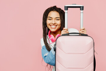 Traveler fun woman wear casual clothes hold suitcase bag isolated on plain pastel pink color background studio. Tourist travel abroad in free spare time rest getaway. Air flight trip journey concept.