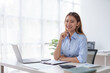 © amnaj - Confident Asian Businesswoman Sitting in Modern Office With Laptop Computer.